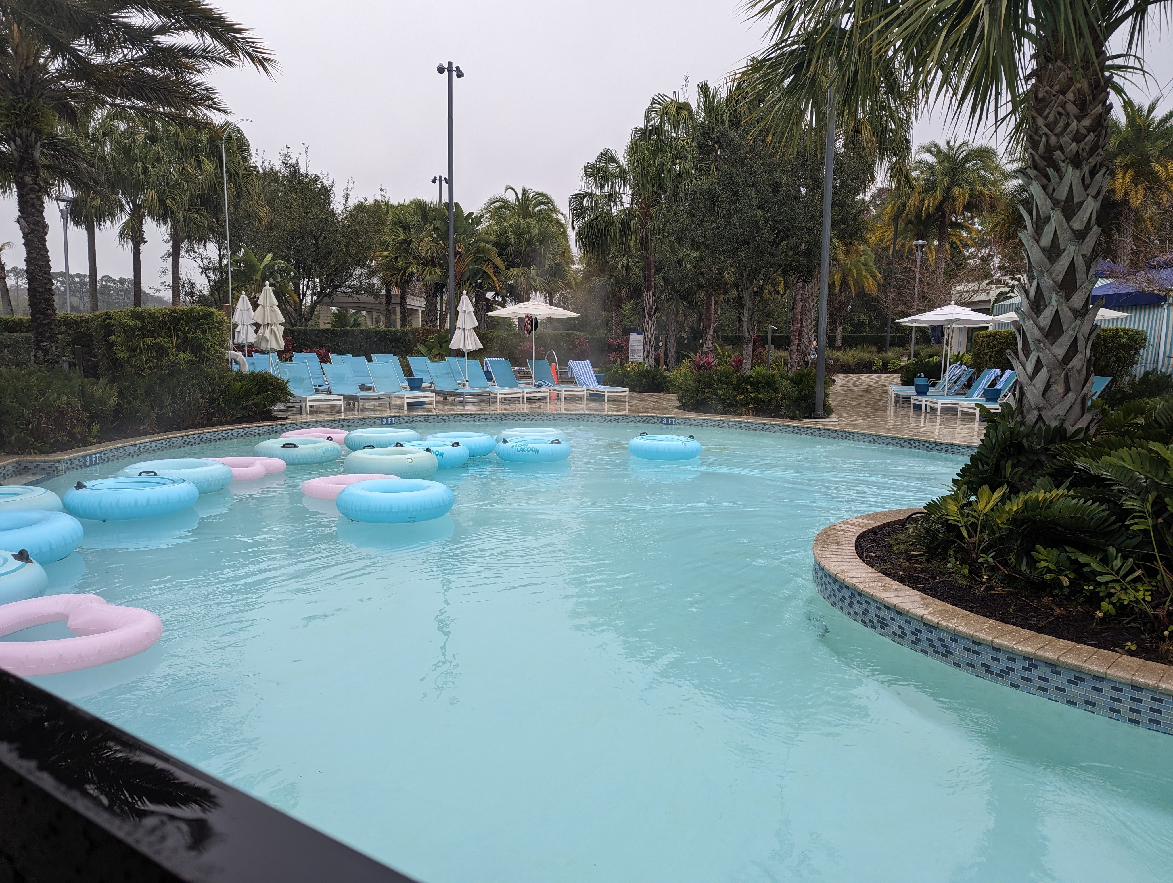 sparkling blue water in a lazy river with blue lounge chairs and pool umbrellas