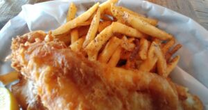 white plate with golden fried fish and French fries.