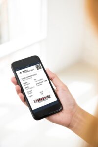 hand with a black cellphone and a electronic boarding pass on the screen