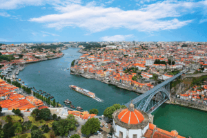 River Cruise ship going through a beautiful old city. White buildings with orange roof tiles are along the riverbanks